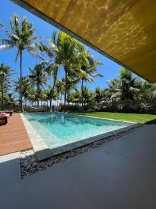 ein Infinity-Pool in einer Villa mit Palmen in der Unterkunft Casa Maçunim 2 in Pôrto de Pedras