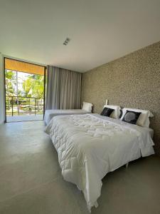 ein großes weißes Bett in einem Schlafzimmer mit einem großen Fenster in der Unterkunft Casa Maçunim 2 in Pôrto de Pedras + 25 Fotos