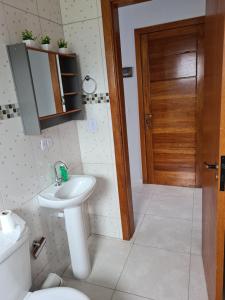 a bathroom with a sink and a toilet and a door at Ap 03 edificio Sao Paulo I in Ponta Grossa