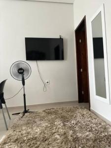 Zimmer mit einem Ventilator und einem TV an der Wand in der Unterkunft Apt C com 2 quarto com ar e garagem in Montes Claros