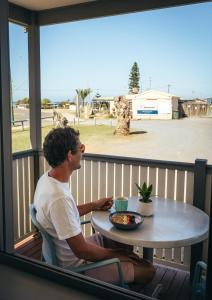 un uomo seduto a un tavolo su un balcone di Horrocks Beach Caravan Park a Horrocks