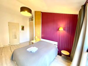 a bedroom with a white bed and a red wall at Le Chêne: medieval district city centre in Poitiers
