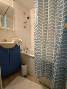a bathroom with a sink and a blue shower curtain at Le Chêne: medieval district city centre in Poitiers