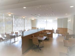 ein Esszimmer mit Tischen, Stühlen und Fenstern in der Unterkunft Urban Hotel Nihonmatsu - Vacation STAY 78339v in Nihommatsu