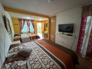 a hotel room with two beds and a flat screen tv at Hotel El Mirador y Jardin in Tlayacapan