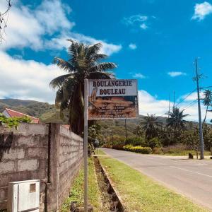 um sinal no lado de uma estrada com uma palmeira em Bungalow climatisé chez Kim em Taputapuapea