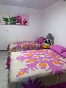 a bedroom with two beds with purple and orange sheets at Bungalow climatisé chez Kim in Taputapuapea