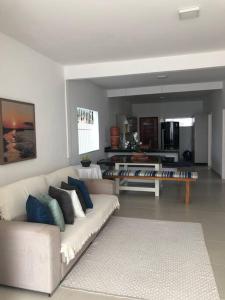 a living room with a white couch and a kitchen at Casa pé na areia em Gamboa do Morro de São Paulo in Cayru