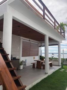 a patio with a table and benches and a staircase at Casa pé na areia em Gamboa do Morro de São Paulo in Cayru