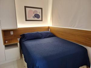 a small bedroom with a blue bed with a wooden headboard at Apartamento novo, perto da praia e conveniências in Salvador