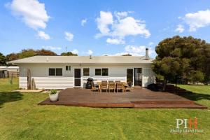 a white house with a deck with tables and chairs at Smith Beach Family House Sleep 6 in Smiths Beach