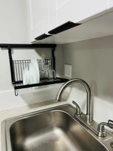 a kitchen sink with two faucets and a shelf above it at Casita Guayaba in Miami