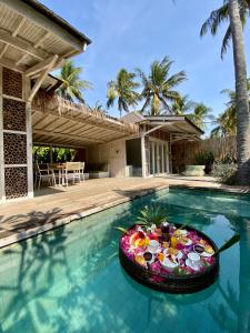 a swimming pool with a bowl of fruit in the water at Villas Edenia in Gili Trawangan