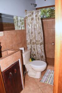 a bathroom with a toilet and a shower curtain at Osa House - Drake Bay in Drake