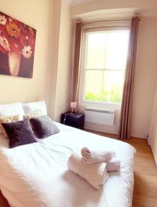 a bedroom with a white bed with a towel on it at UK Chaps Retreat: Balcony Apartment in London