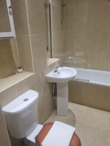 a bathroom with a toilet and a sink and a tub at UK Chaps Retreat: Balcony Apartment in London