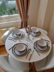 a white table with plates and wine glasses on it at UK Chaps Retreat: Balcony Apartment in London