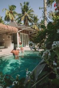 a man and a child in a swimming pool at Villas Edenia in Gili Trawangan