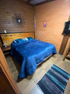 ein Schlafzimmer mit einem blauen Bett und einer Holzwand in der Unterkunft Cabanas dos Sonhos Barra de Ibiraquera in Imbituba