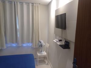 a room with a bed and a tv and a fan at Casa de Esquina Nova in Garanhuns