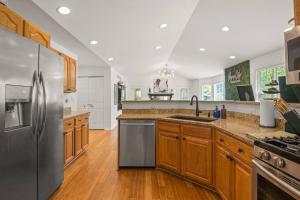a kitchen with a stainless steel refrigerator and wooden cabinets at Delight: Bold & Bougie! Sleeps 12! Downtown Boyne in Boyne City
