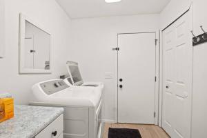 a white bathroom with a sink and a washing machine at Delight: Bold & Bougie! Sleeps 12! Downtown Boyne in Boyne City +45 photos