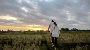 a man and a woman walking through a field at Kusfarm Bali by AHM in Selemadeg