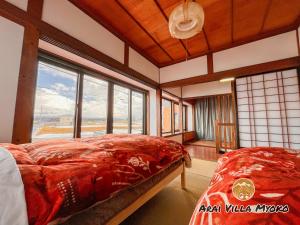 a bedroom with a bed and a large window at Arai Villa Myoko in Myoko