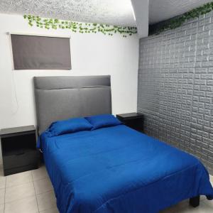 una camera con letto blu e muro di mattoni di El Hostalito Metepec a Toluca