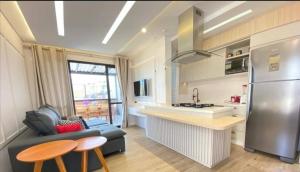a kitchen and living room with a couch and a refrigerator at Cobertura Palmas in Governador Celso Ramos