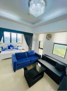 a living room with a blue couch and a bed at Splendido Tower 2 Ann's Unit in Tagaytay