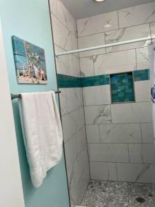 y baño con ducha y toalla blanca. en Cedar Key Florida Condo at Park Place en Cedar Key