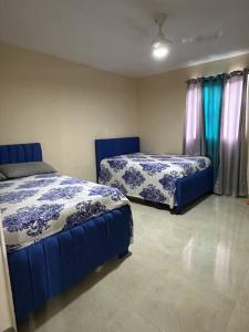 a bedroom with two blue beds and curtains at Villa Richie's House RD. 