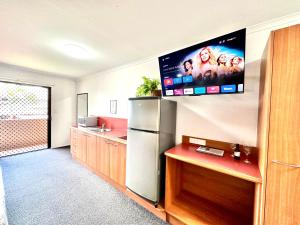 a kitchen with a refrigerator and a tv on the wall at Mackay Resort Motel in Mackay
