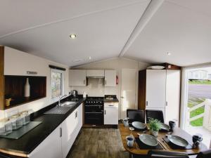 a kitchen with a table and a sink and a counter at Beautiful 8 Berth Caravan At Valley Farm Holiday Park, Essex Ref 46362v in Great Clacton