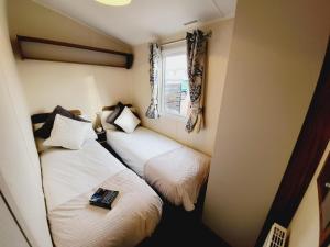 Duas camas num pequeno quarto com uma janela em Beautiful 8 Berth Caravan At Valley Farm Holiday Park, Essex Ref 46362v em Great Clacton