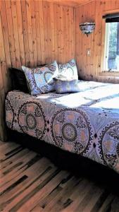 Bett in einem Zimmer mit Holzwänden in der Unterkunft Treetop Cottage-Dog Friendly No Fees, Mill Lake, Hot Tub, Kayak, Paddle Boat, Row Boat, Firepit in Gobles