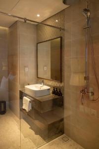 a bathroom with a sink and a mirror and a shower at M Continental by Mandala Mui Ne in Phan Thiet