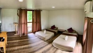a room with two beds and a large window at โฮมสเตย์ตานงค์ อำเภอปัว in Nan