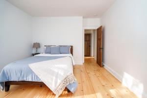a white bedroom with a bed and a wooden floor at Very Cozy, 2 Bedroom Farmhouse Apartment 2nd FL in Lancaster