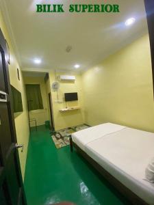 a bedroom with a bed and a green floor at Fadlim Homestay in Padang Serai