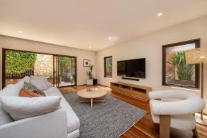 ein Wohnzimmer mit einem Sofa und einem TV in der Unterkunft Esplanade Escape to the Brighton Beach Boxes in Melbourne