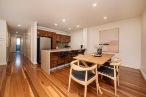 cocina y comedor con mesa de madera y sillas en Esplanade Escape to the Brighton Beach Boxes en Melbourne