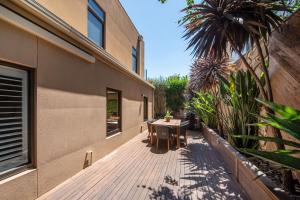 una terraza de madera con mesa y un edificio en Esplanade Escape to the Brighton Beach Boxes, en Melbourne