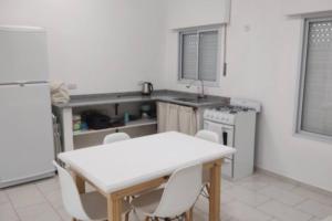 uma cozinha com uma mesa branca e cadeiras brancas em Casa en Gualeguaychú em Gualeguaychú