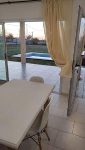 Una mesa blanca y una silla en una habitación con piscina en Casa en Gualeguaychú en Gualeguaychú
