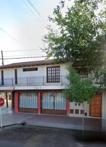 um edifício branco com uma varanda e uma árvore em La Primi em Guaymallén