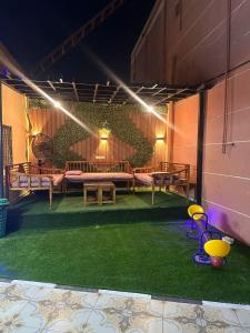 eine Terrasse mit Bänken und grünem Gras in der Nacht in der Unterkunft شاليهات هدوء الشاطئ لبيوت العطلات in Ar Rukūbah