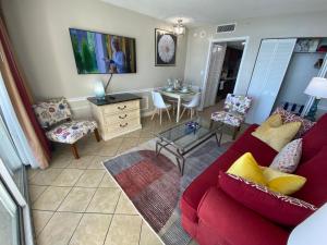 - un salon avec un canapé rouge et une table dans l'établissement Camelot By The Sea Ocean Front Condo, à Myrtle Beach