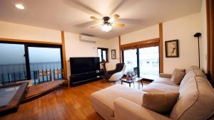 a living room with a couch and a flat screen tv at 丘の上の隠れ家邸宅 Villa VIEW in Nanjo